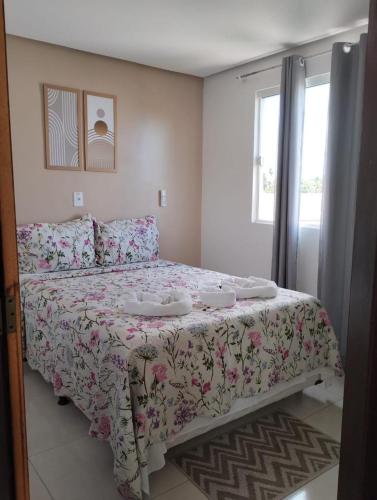 a bedroom with a bed with a floral bedspread at Pousada La Belle in Maragogi