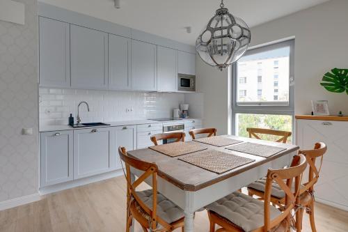een keuken met witte kasten en een tafel en stoelen bij Wave Apartments - SILVER NADMORZE in Gdańsk