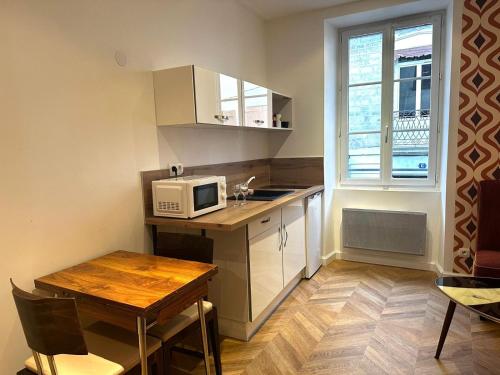 een kleine keuken met een tafel en een magnetron bij Seventies, vintage et bohème in Bourgoin