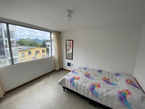 - une chambre avec un lit et une grande fenêtre dans l'établissement Apartamento Belen, à Manizales