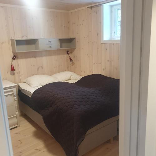 a bedroom with a bed with a black comforter at Brekkveien 81-meget sentral hytte,15 min å gå til Røros sentrum in Røros