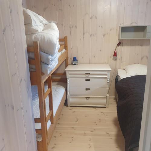 a bedroom with two bunk beds and a night stand at Brekkveien 81-meget sentral hytte,15 min å gå til Røros sentrum in Røros