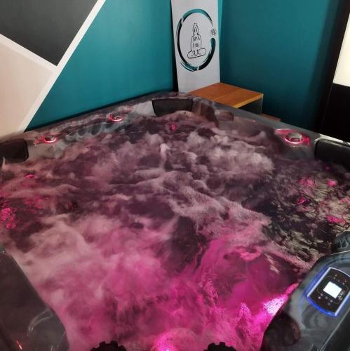 - une baignoire remplie d'eau rose dans la chambre dans l'établissement AJC Ô Spa, à Saulzoir