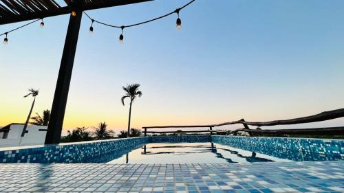 a swimming pool with a view of the ocean and palm trees at Hotel MAYARI Holbox in Holbox Island