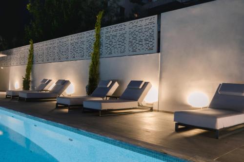 a group of lounge chairs next to a swimming pool at Brasil Suites Boutique Hotel in Athens