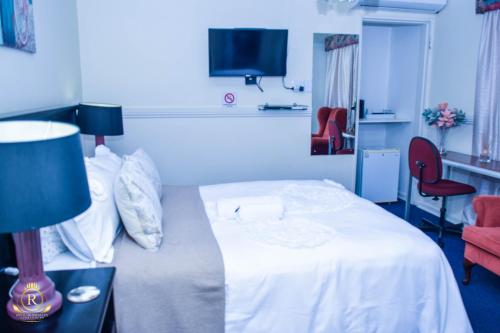 a bedroom with a white bed and a red chair at Royal Highness Lux Guesthouse in Carletonville
