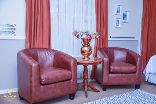 two chairs and a table with a vase of flowers at Royal Highness Lux Guesthouse in Carletonville
