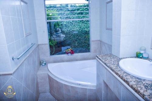 baño con 2 lavabos, bañera y ventana en Royal Highness Lux Guesthouse, en Carletonville