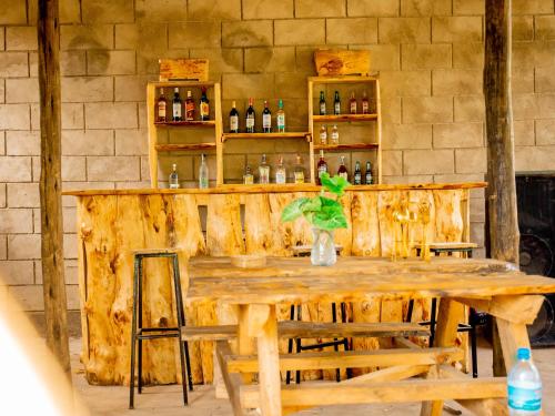 einen Holztisch in einem Zimmer mit einer Theke mit Flaschen in der Unterkunft Arusha Jua home in Arusha