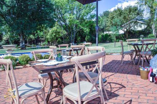 a wooden table and chairs on a brick patio at Royal Highness Lux Guesthouse in Carletonville
