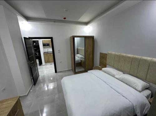 una camera con letto bianco e specchio di رويال جروب للشقق الفندقية a Irbid