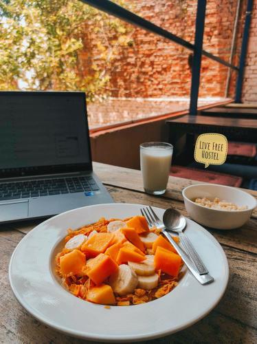 a plate of food on a table next to a laptop at Live Free Hostel Varanasi in Varanasi