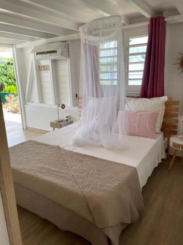 a bedroom with a large white bed with pink pillows at Bungalow Candy avec piscine in Rivière-Salée