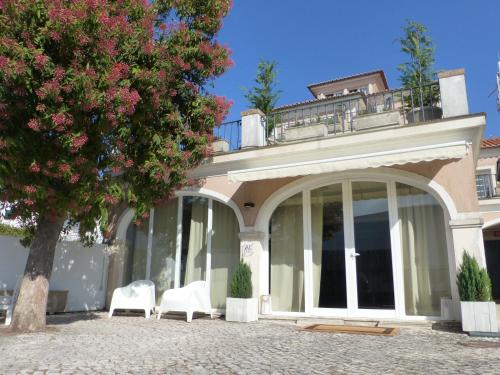 a house with two white chairs and a tree at Cosy Sintra in Sintra