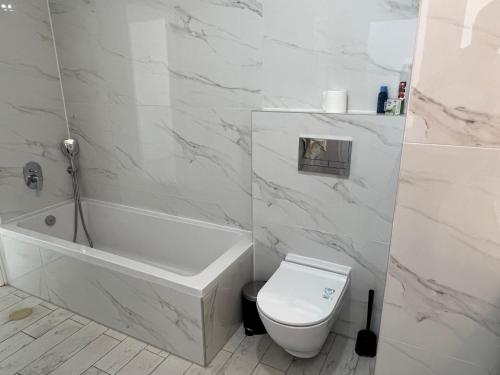 een witte badkamer met een toilet, een bad en een wastafel bij Prince Palace Hadera Beach in H̱adera