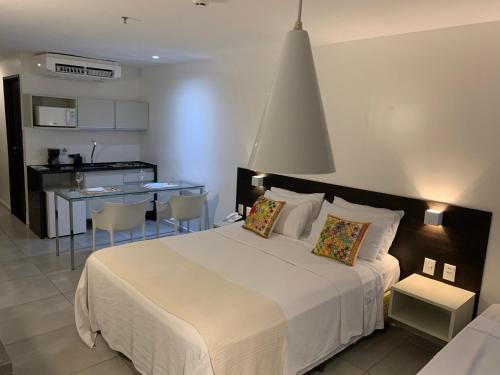 una camera con un grande letto bianco e una cucina di Coral Ritz - Flat beira mar (Condomínio Ritz Suites Home Service) a Maceió