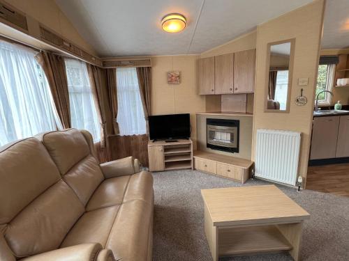a living room with a couch and a television at Poppy at Oakdene Forest Park in Ringwood