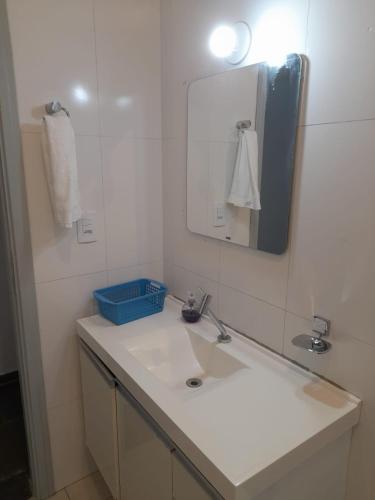 a white bathroom with a sink and a mirror at Quarto com duas camas de solteiro in Itu