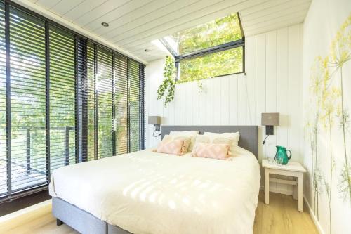 een slaapkamer met een bed en een groot raam bij Onder het dak van Brabant in Mierlo