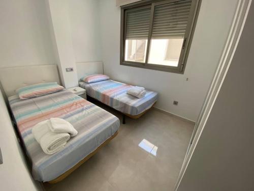 two beds in a small room with a window at Villa Murcia Paradise in Los Alcázares