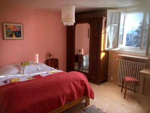 a bedroom with a bed with a red blanket and a window at Appartement montagne Le Revard in Pugny-Chatenod