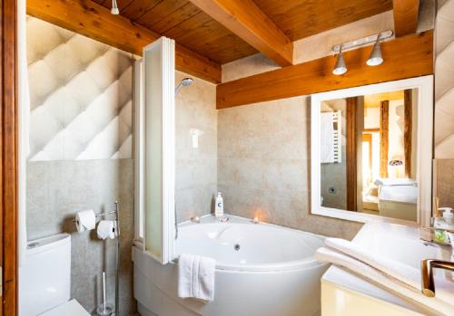a bathroom with a tub and a sink and a mirror at Apartamentos Vino Tinto y Restaurante Tomate Rosa in Adahuesca