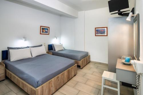 a hotel room with two beds and a tv at Honeymoon Beach Studios in Perivolos