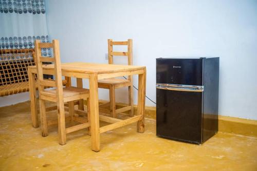 a table and chairs next to a table and a refrigerator at Bara Accommodations Paje in Paje