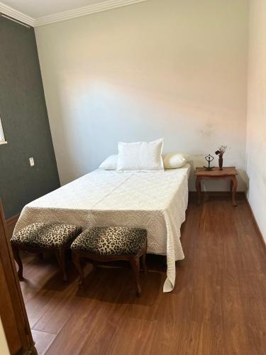 a bedroom with a bed and a table and stool at Casa Grande Hospedagem in Brumadinho