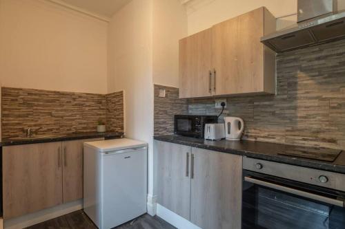 eine Küche mit Holzschränken und einem weißen Kühlschrank in der Unterkunft Urban Stay: Studio Suite 8 in Parkside