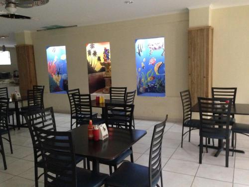 a dining room with tables and chairs and paintings on the wall at Hotel Carnaval in La Ceiba