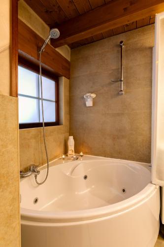 a large white tub in a bathroom with a window at Apartamentos Vino Tinto y Restaurante Tomate Rosa in Adahuesca