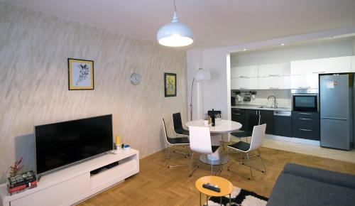 ein Wohnzimmer mit einem TV und einem Tisch mit Stühlen in der Unterkunft City Osijek, CENTAR, SELF CHECK IN in Osijek