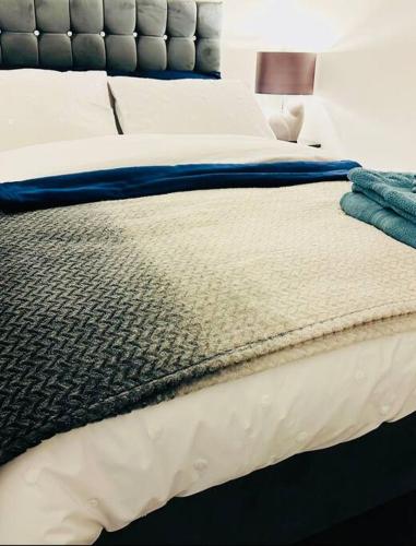 a bed with a blue and white comforter on it at 1 Luxe Exec Bedroom Apt Derby in Derby