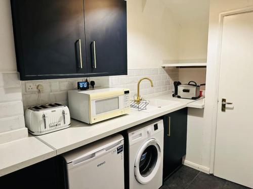 a kitchen with a washing machine and a microwave at 1 Luxe Exec Bedroom Apt Derby in Derby