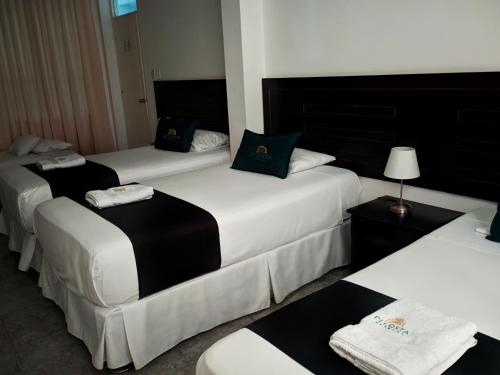 3 Betten in einem Hotelzimmer mit Handtüchern darauf in der Unterkunft Di Costa Hotel in Piura