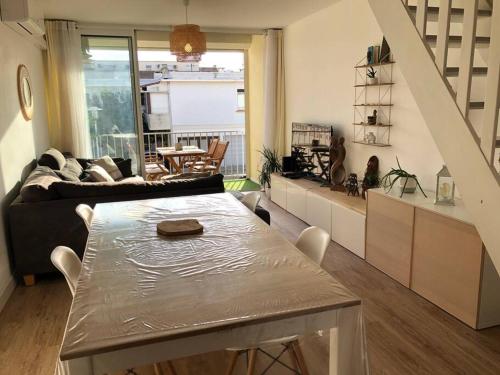 a living room with a table and a couch at Le Corail - Superbe Duplex 3 chambres 6 personnes in Le Grau-du-Roi
