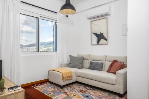 a living room with a couch and a window at Casa da Angela - By WeHost in Funchal