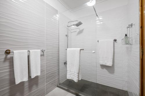 uma casa de banho com toalhas brancas e uma cabina de duche em vidro. em Casa da Angela no Funchal
