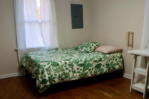 a bedroom with a bed with a green and white blanket at Cozy East Haven Apartment - Walk to Beach! in East Haven