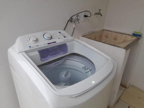 a washing machine with its door open in a bathroom at Suíte com uma cama de casal e uma cama de solteiro in Itu