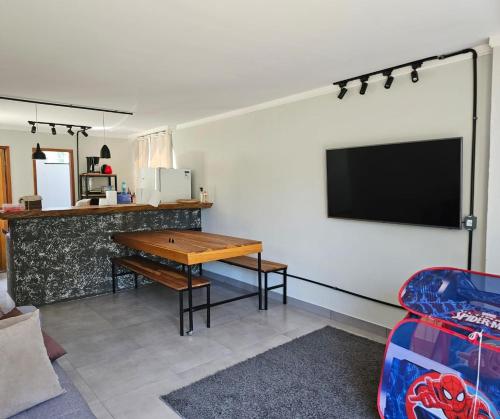 a living room with a table and a tv on a wall at CASA DINAMARCA in Santa Teresa