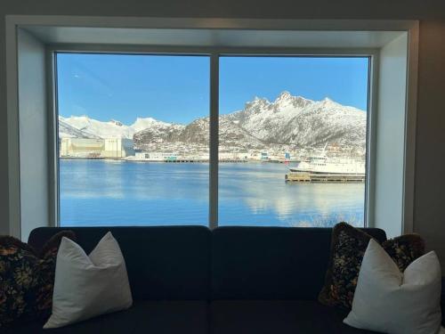 a large window with a view of the water and mountains at Sentrumsnær leilighet med utsikt in Svolvær