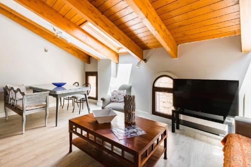 a living room with a television and a table at Apartamentos Vino Tinto y Restaurante Tomate Rosa in Adahuesca