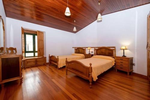 um quarto com 2 camas e piso em madeira em Casa rural de uso turístico Playa de Carnota em Canedó