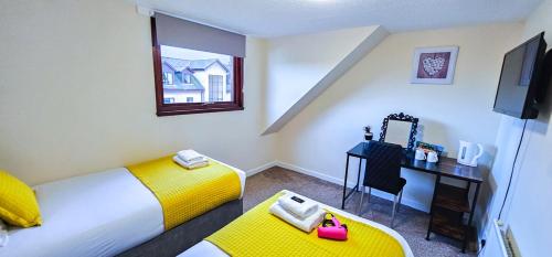 a room with two beds and a desk and a television at mySTAYINN Telford Guest House in Inverness