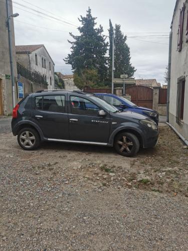 une voiture noire garée sur le côté d'une rue dans l'établissement Maison de village, à Ventenac-Cabardès