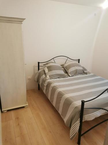 a bed in a white bedroom with a wooden floor at Maison de village in Ventenac-Cabardès