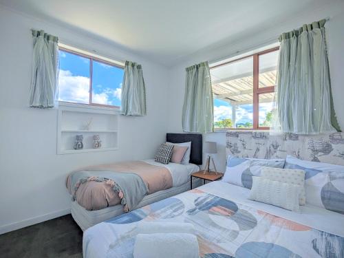two beds and a couch in a room with windows at 4 Bedrooms Escape, close to CBD in Rotorua