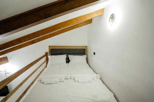 a bed in a white room with a staircase at Casa Mecva in Borşa